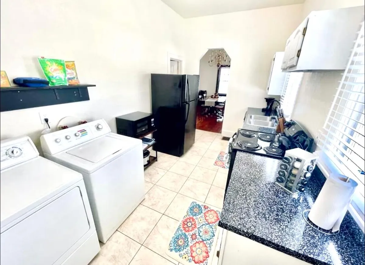 A practical laundry area with a washer and dryer adjacent to a modern kitchen space. The area feels cozy yet functional, integrating laundry amenities into the everyday rhythm of home life—ideal for both short and extended stays.