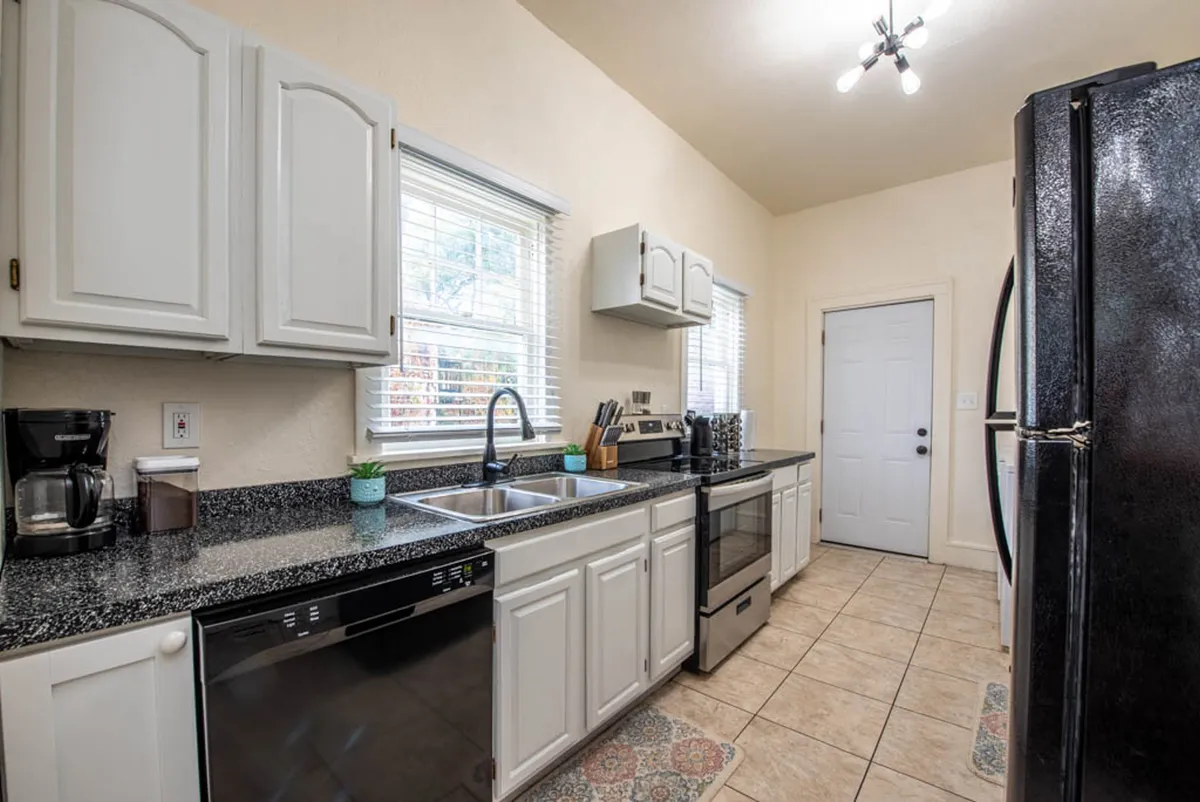 This image showcases a kitchen with granite countertops, stainless steel appliances, a window providing natural light, and a kitchen sink. The space feels cozy yet highly functional, perfect for meal prep and socializing during gatherings.
